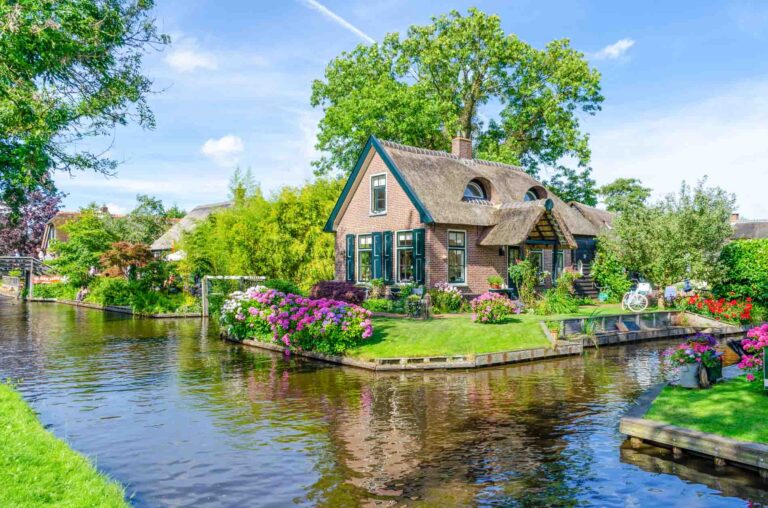 GIETHOORN, NETHERLANDS - JULY 17,2016: Landscape view of famous Giethoorn village with canals and rustic thatched roof houses. The beautiful houses and gardening city is know as "Venice of the North".